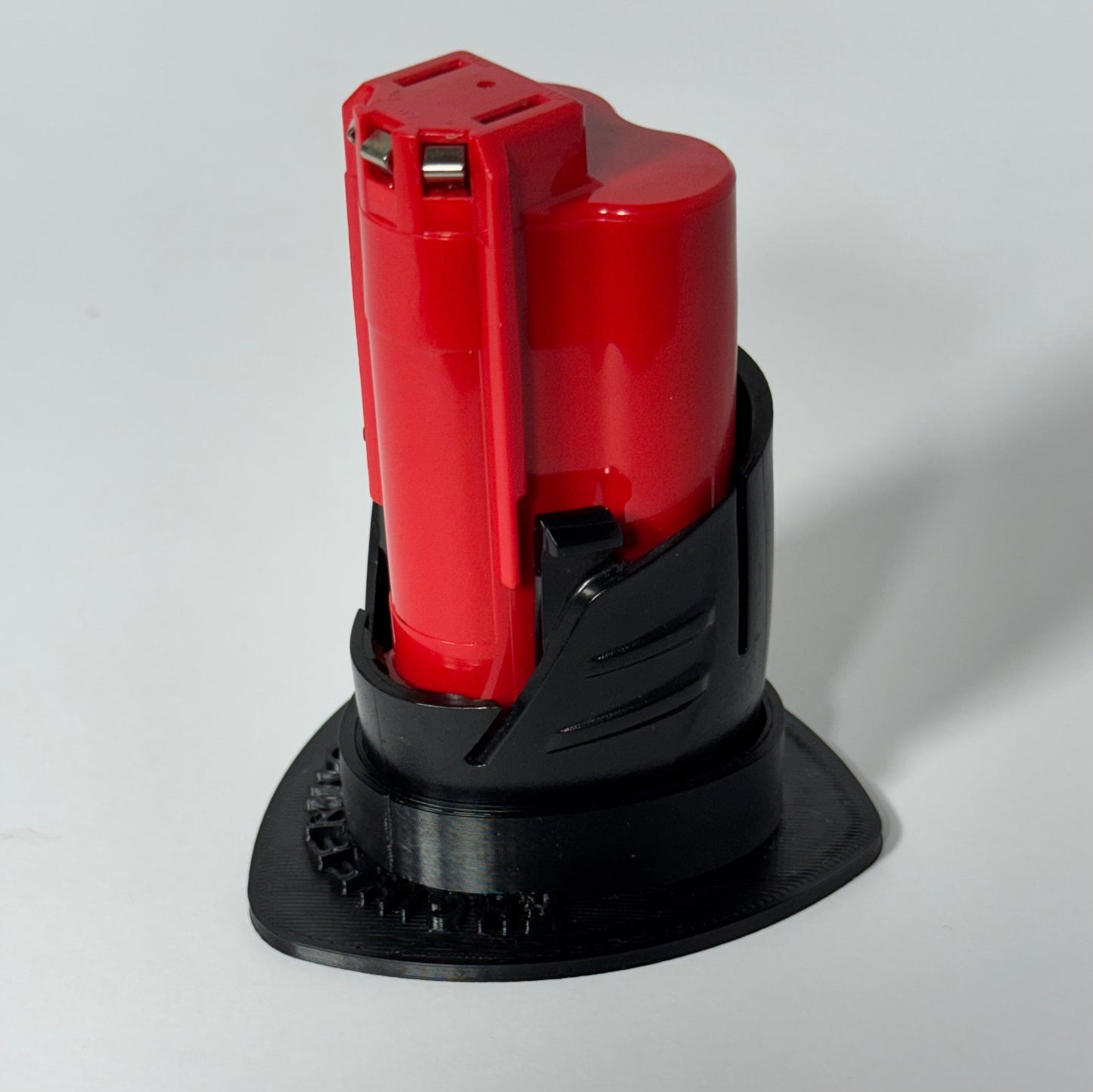 Magnetic storage base for Milwaukee M12 batteries, designed for stability and easy metal surface mounting.