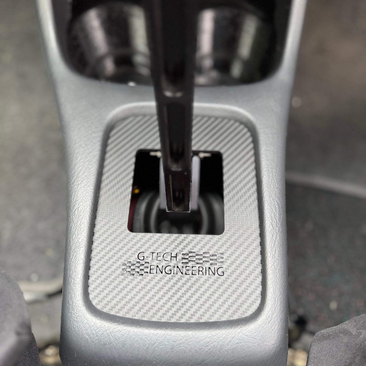 Close-up of carbon-reinforced Honda Civic EK shift plate – performance aftermarket transmission part.