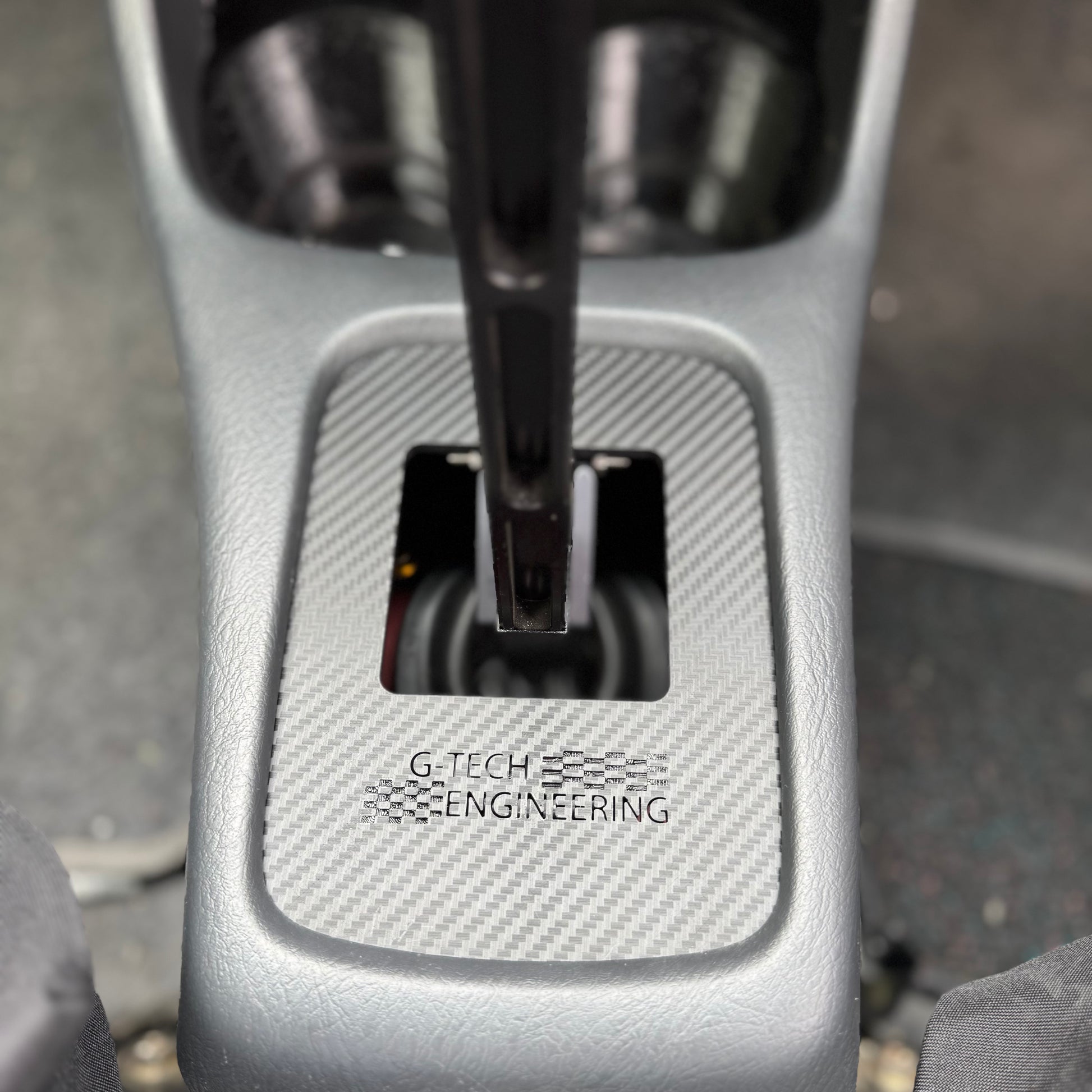 Close-up of carbon-reinforced Honda Civic EK shift plate – performance aftermarket transmission part.